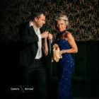 Debby in een blauwe pailletjurk en Emiel in smoking poseren met een rauwe kip en twee verse vissen.
